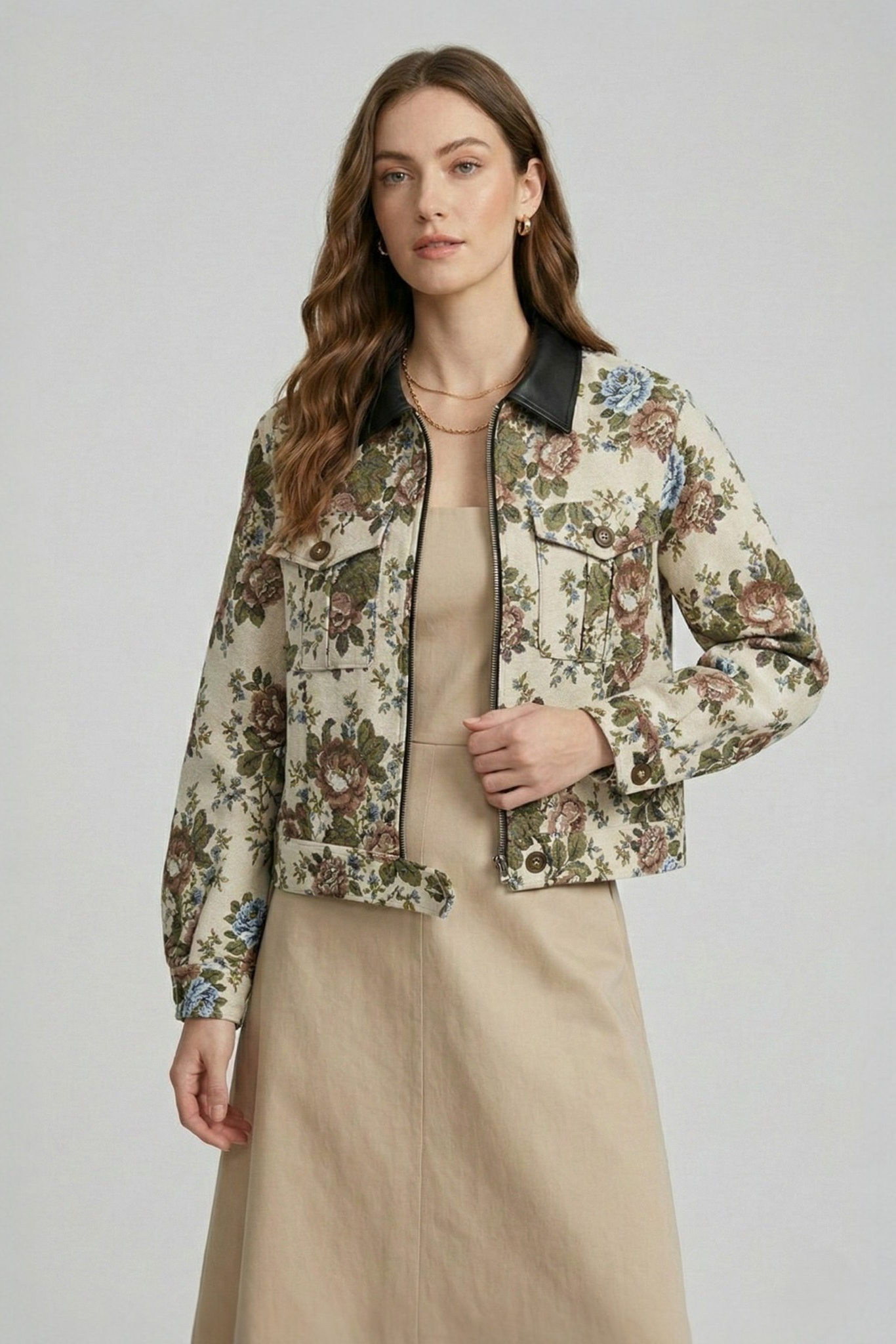 A model wearing a beige floral jacquard cropped jacket with a black collar, styled with a matching dress. 