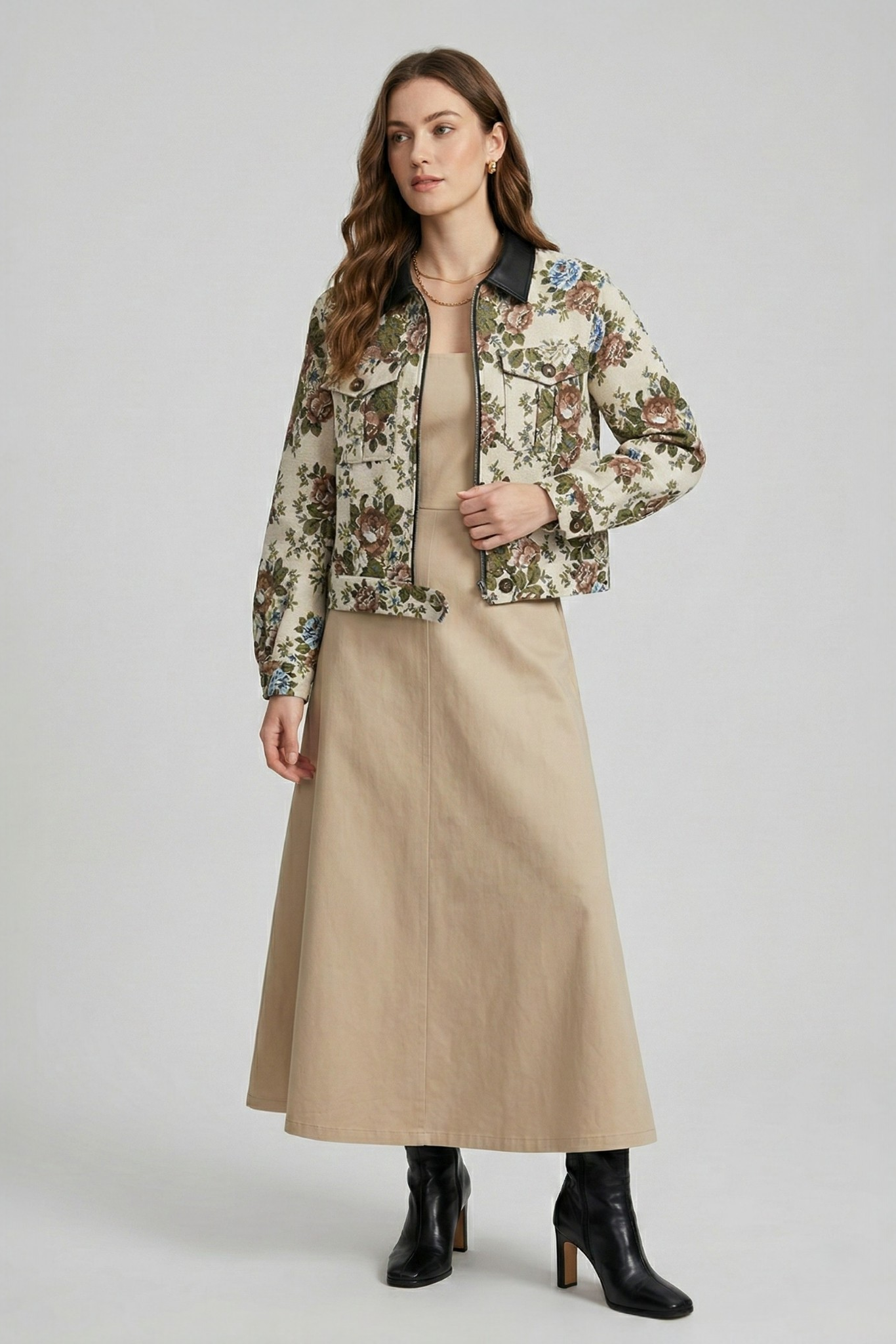 A model wearing a beige floral jacquard cropped jacket with a black collar, styled with a matching dress and black boots.