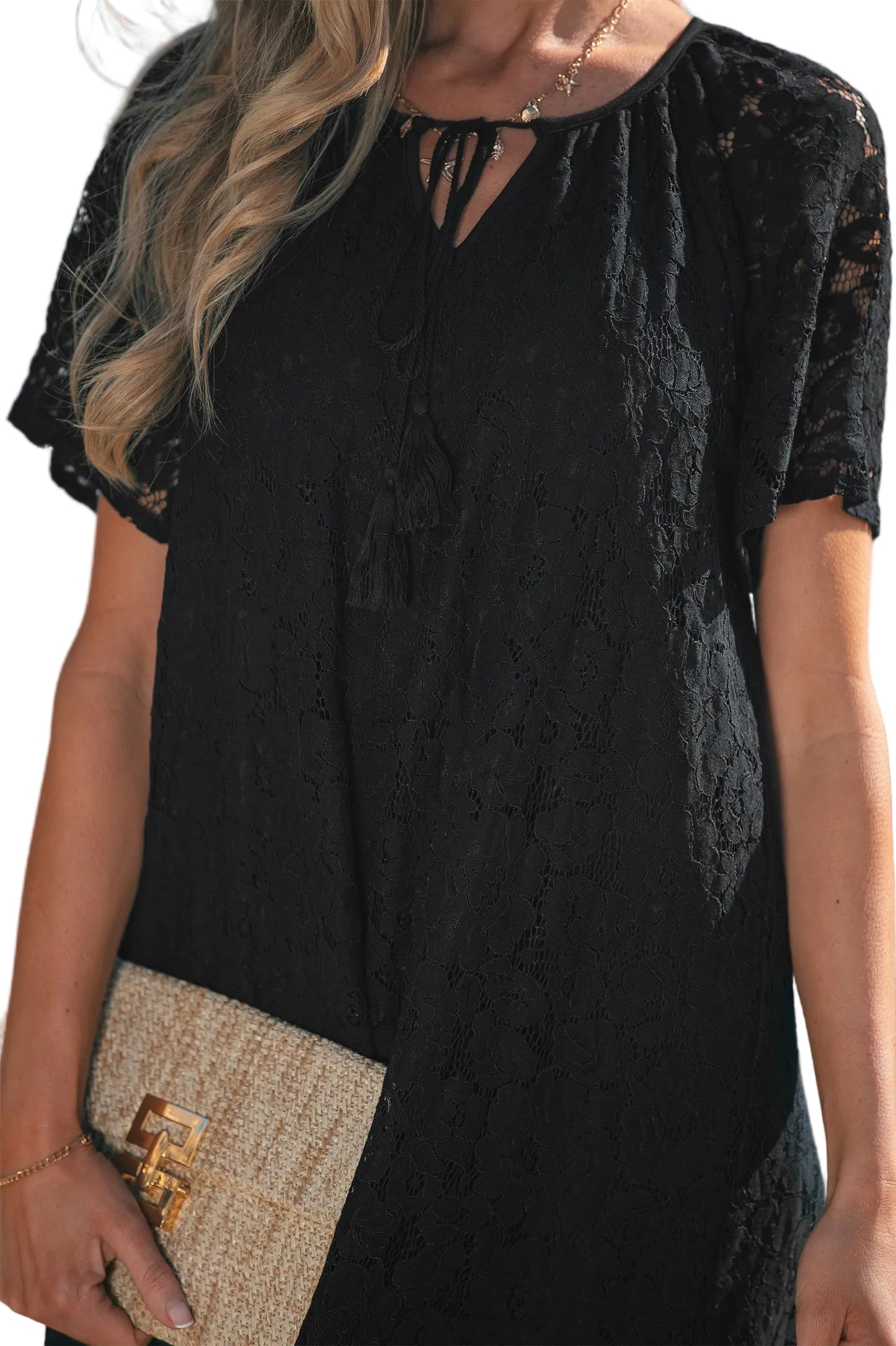 Black lace dress with a beige clutch held by a person