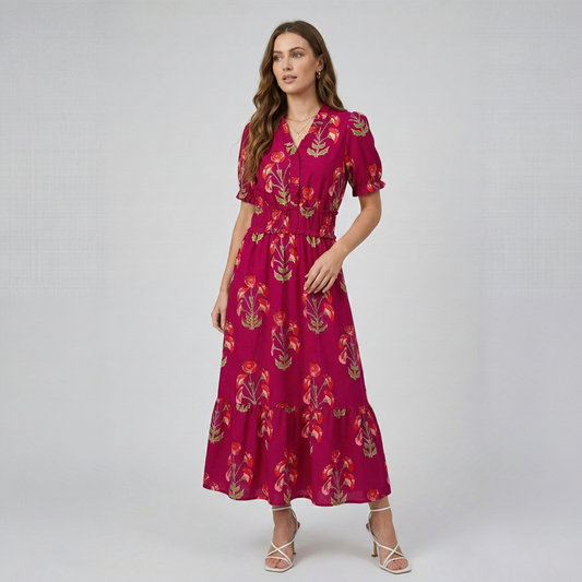 Model posing in a fuchsia floral print tiered maxi dress with v-neck and short sleeves, full-body front view.