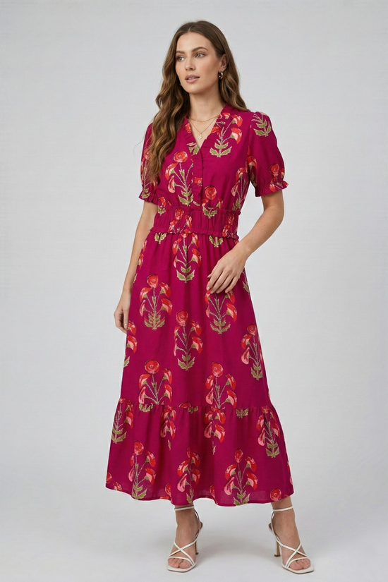 Model posing in a fuchsia floral print tiered maxi dress with v-neck and short sleeves, full-body front view.