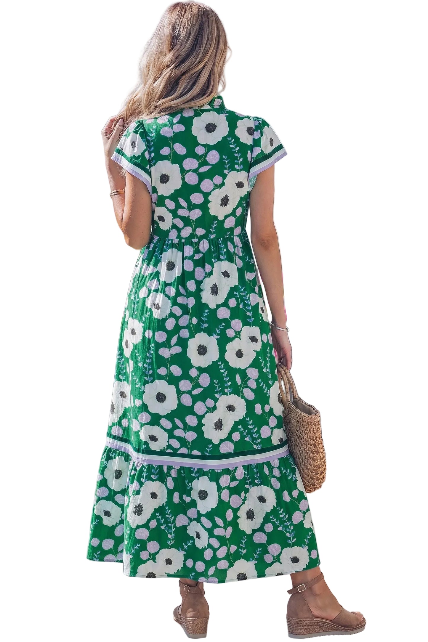Back profile of a woman wearing a green floral dress with short flutter sleeves and V-neckline standing against a white background