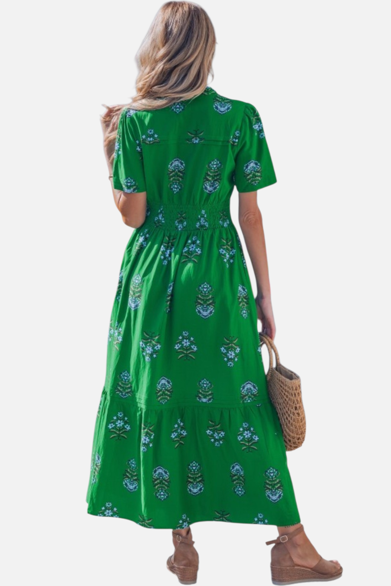 Rear view of a model in a vibrant green floral maxi dress, showcasing the shirred elastic waistband, short puff sleeves, and a tiered ruffled hem.