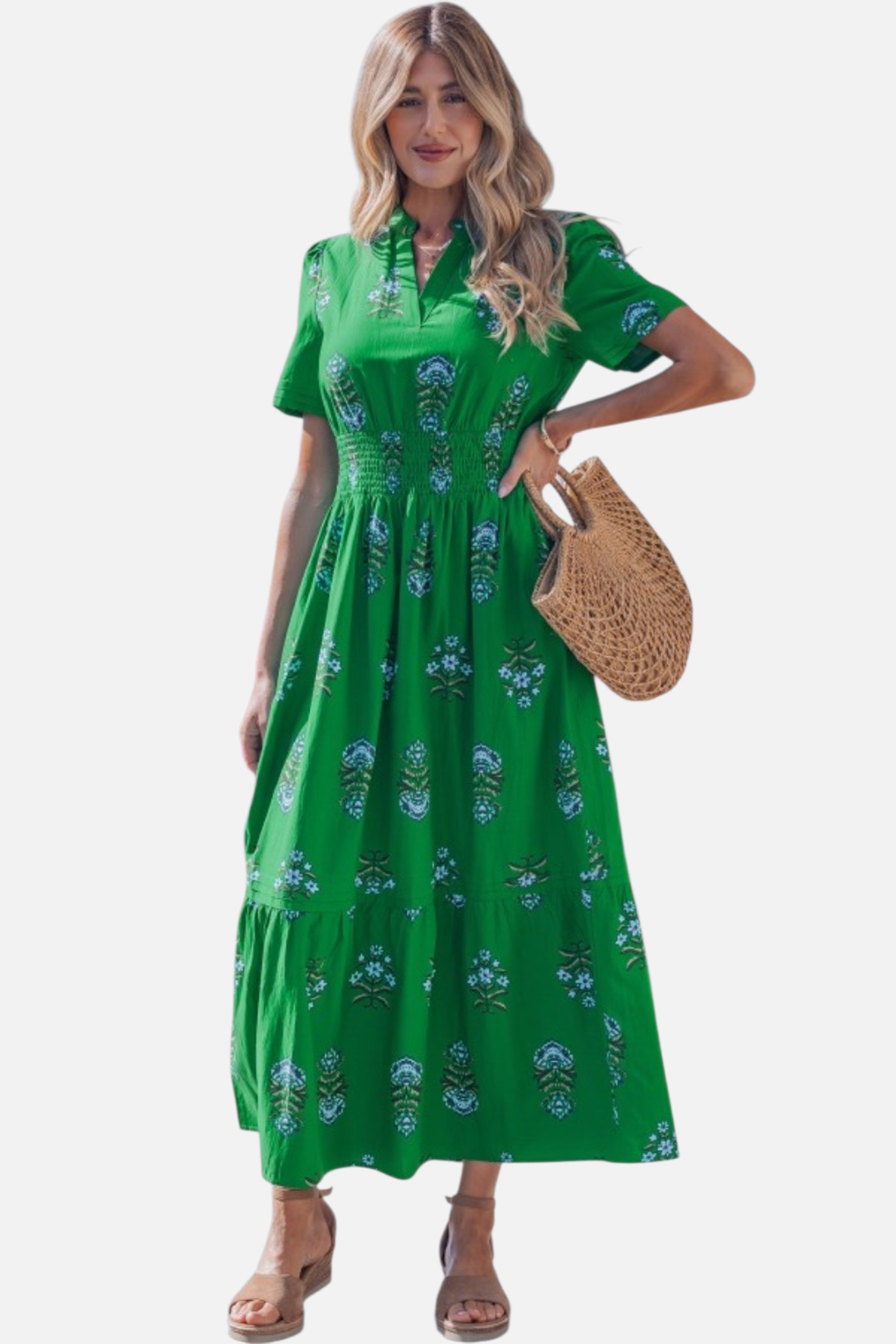 Woman wearing a green floral dress holding a straw bag on a white background