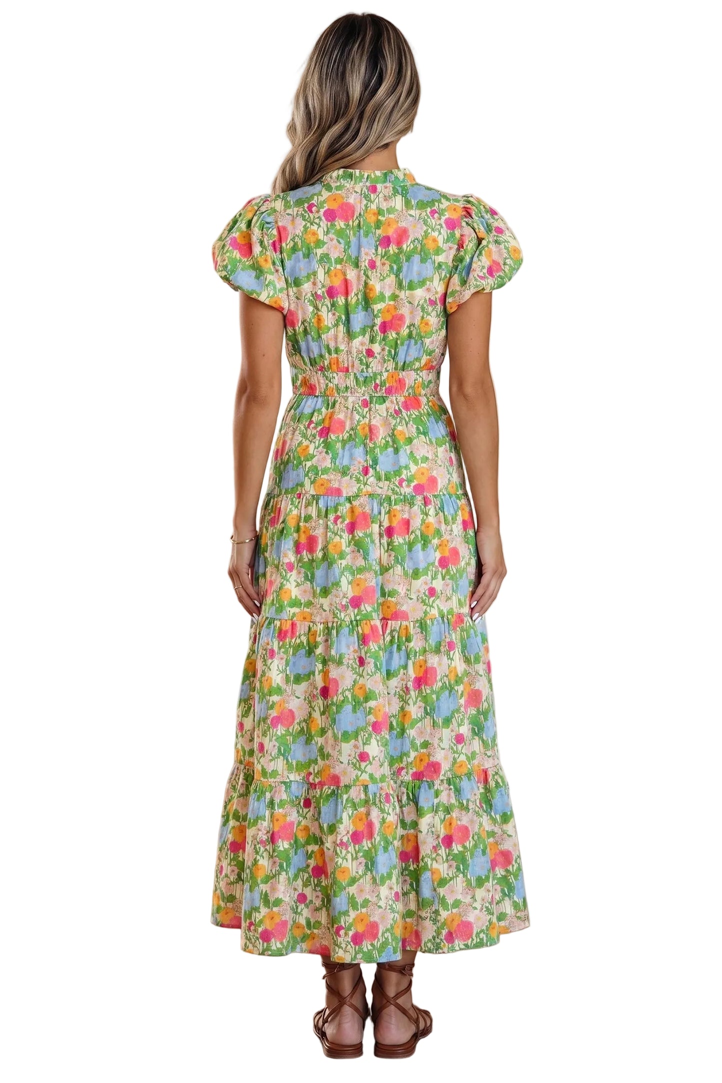 Woman wearing a colorful floral dress in a room with wooden floor and beige walls.