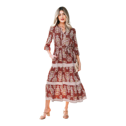 Woman wearing a rust-brown paisley floral maxi dress with a matching waist tie belt and flutter sleeves.