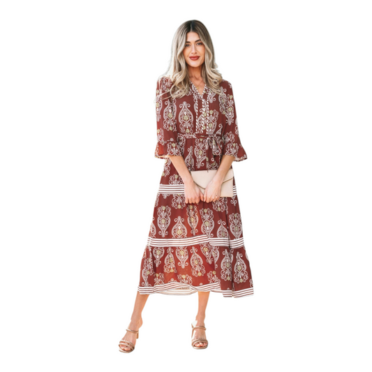 Woman wearing a rust-brown paisley floral maxi dress with a matching waist tie belt and flutter sleeves.