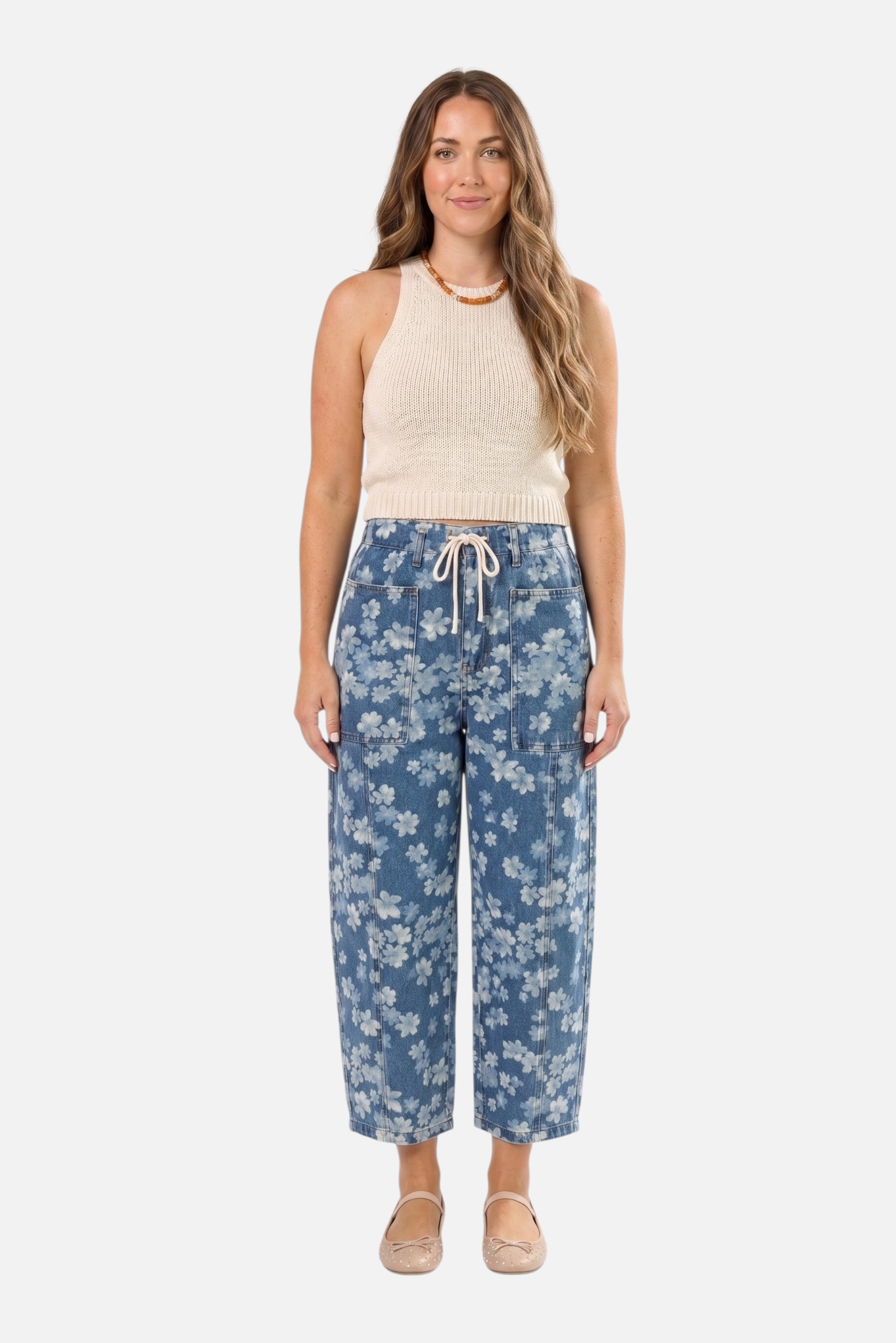 Full-length front view of a model wearing light blue floral print barrel jeans with a relaxed wide-leg fit and an adjustable cream drawstring waist.
