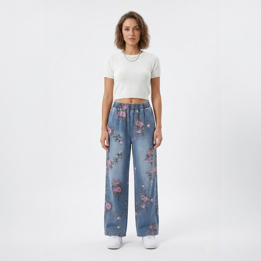 Full-length front view of a model showcasing the relaxed fit of blue denim wide-leg jeans featuring an all-over vintage rose floral pattern.