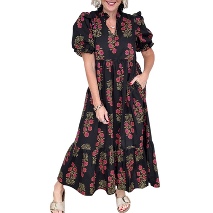 Woman wearing a black and pink floral cotton midi dress with puff sleeves and a tiered ruffle hem.