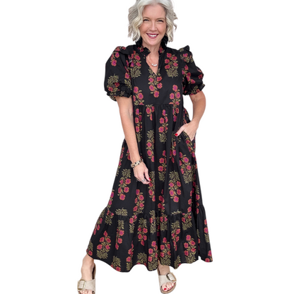 Woman wearing a black and pink floral cotton midi dress with puff sleeves and a tiered ruffle hem.