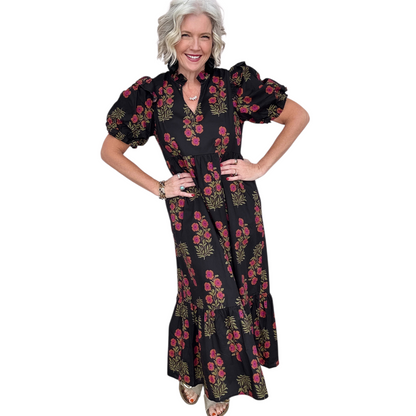 Woman wearing a black and pink floral cotton midi dress with puff sleeves and a tiered ruffle hem.