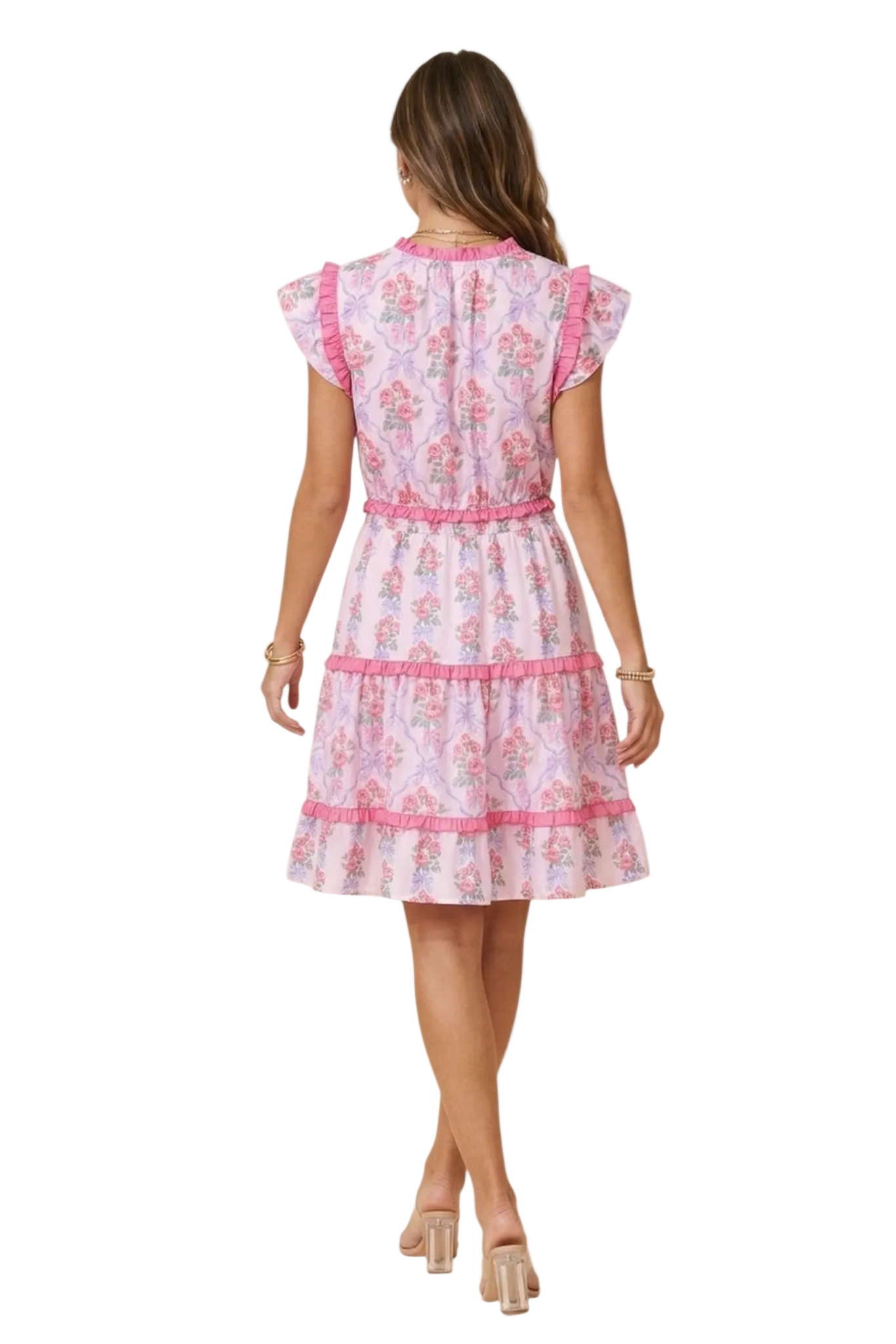 Rear view of a model in a pink tiered floral mini dress, highlighting the smocked elastic waist and ruffled skirt layers.