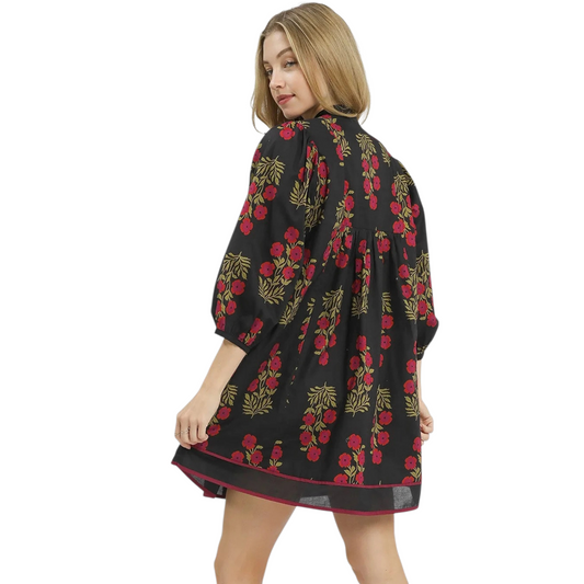 Rear view of a black floral mini dress showing a relaxed A-line silhouette, bracelet-length sleeves, and a gathered back detail.