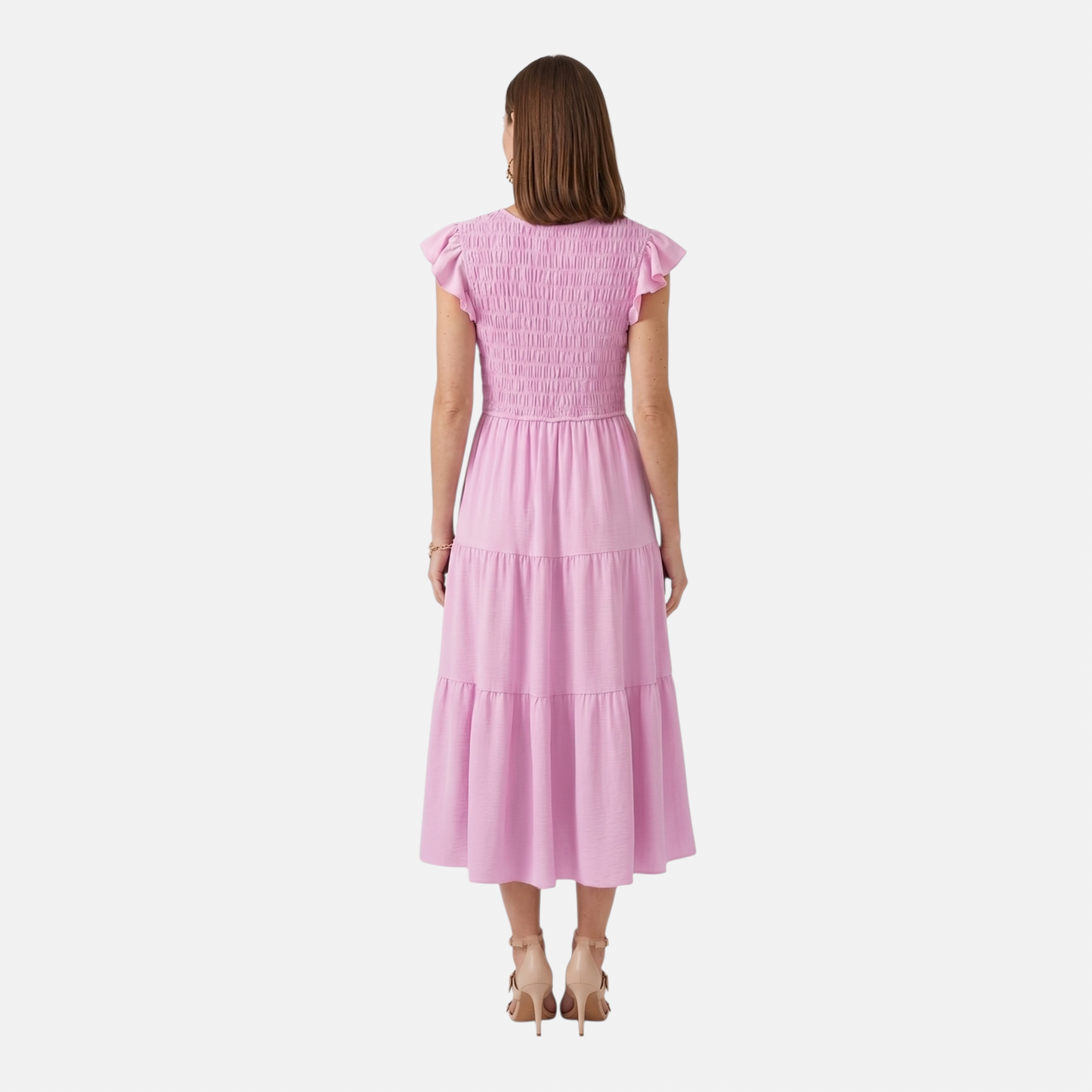 The back view of a woman in a light pink smocked midi dress. The smocking extends across the entire back of the bodice, leading into a three-tiered skirt that hits at mid-calf.