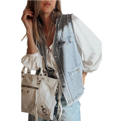 Person wearing a light blue denim vest over a white blouse, holding a beige handbag.