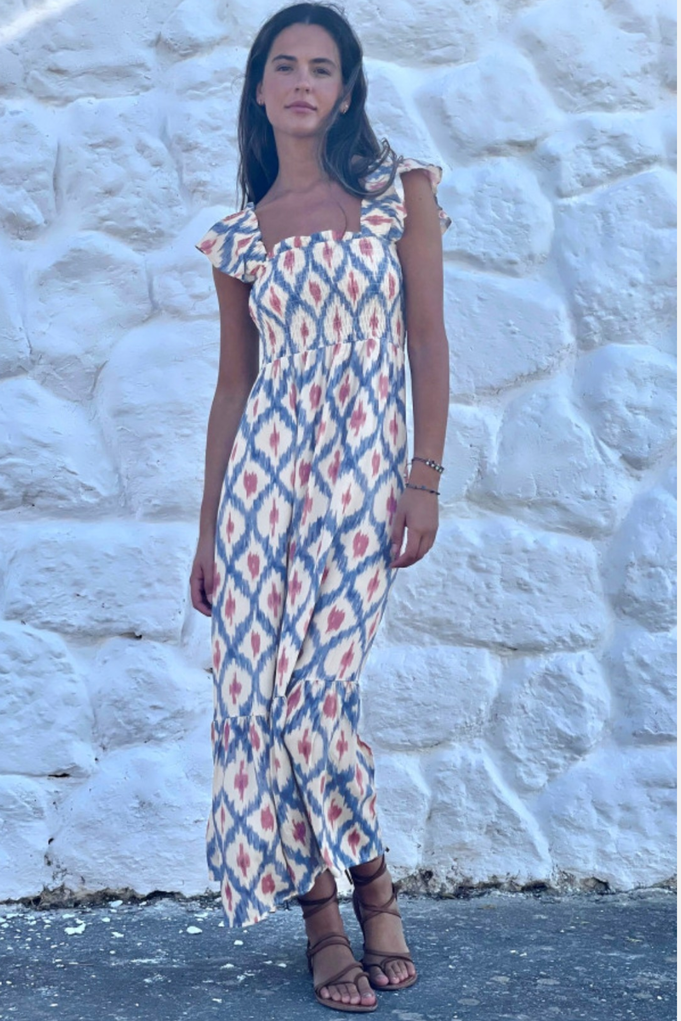 Lifestyle shot of the square-neck maxi dress against a white stone wall, highlighting the breezy viscose fabric and bohemian aesthetic.