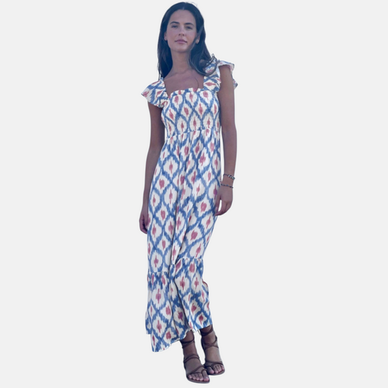 Full-length studio view of a model in a geometric print maxi dress featuring a smocked high-waist bodice and tiered ruffle hem.