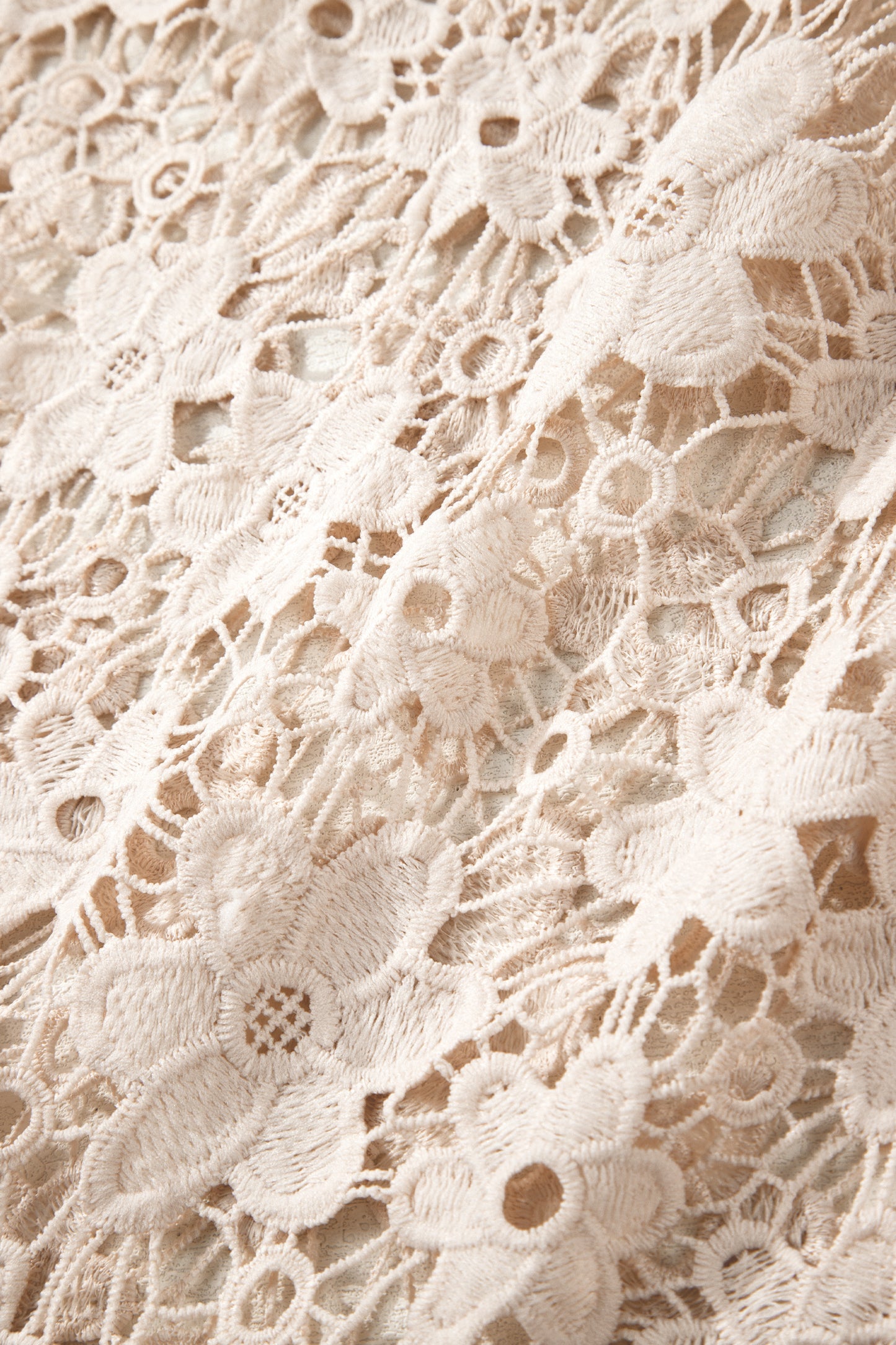 Close-up of beige lace fabric with intricate patterns