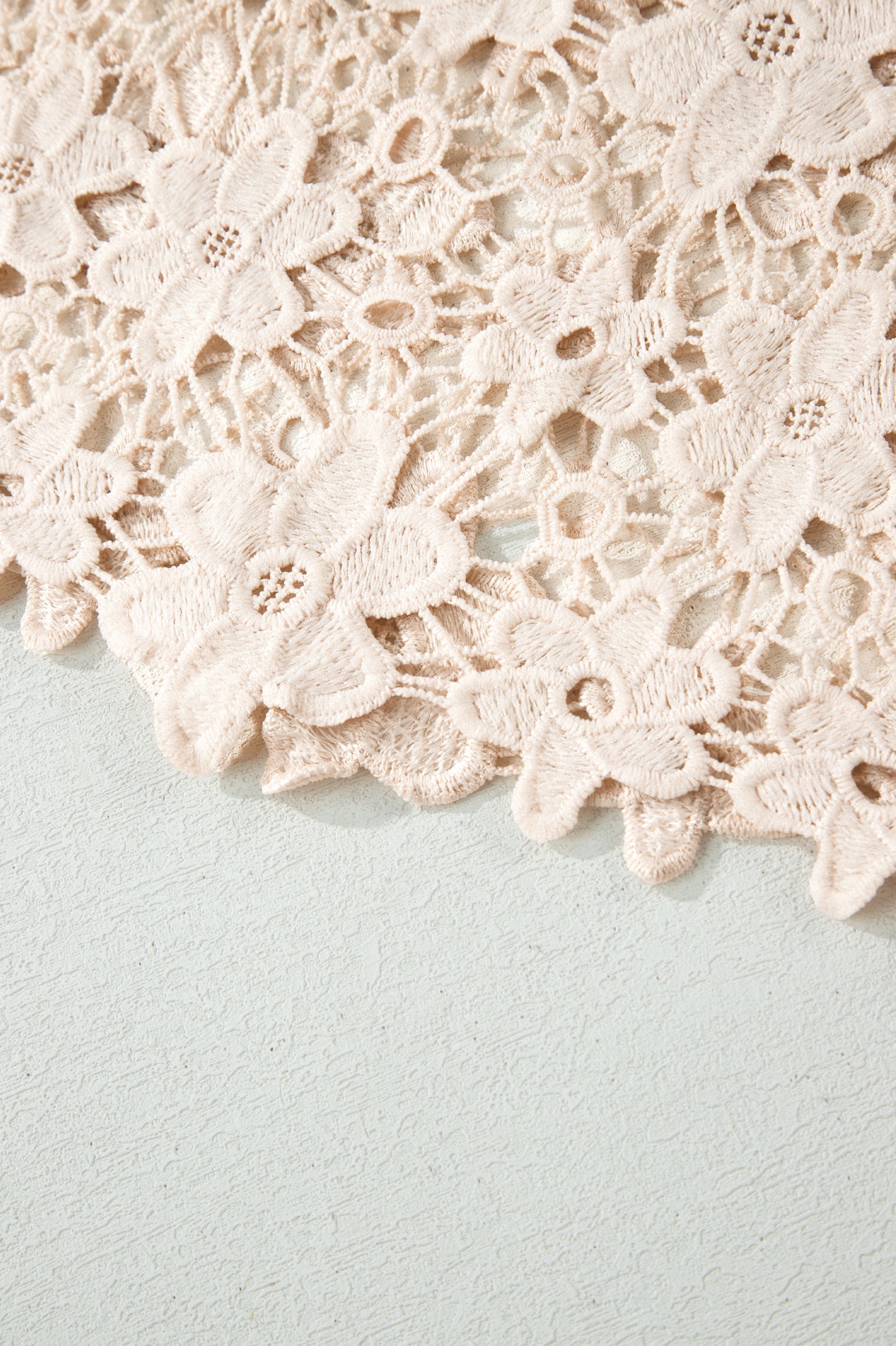 Close-up of beige lace fabric on a light blue background