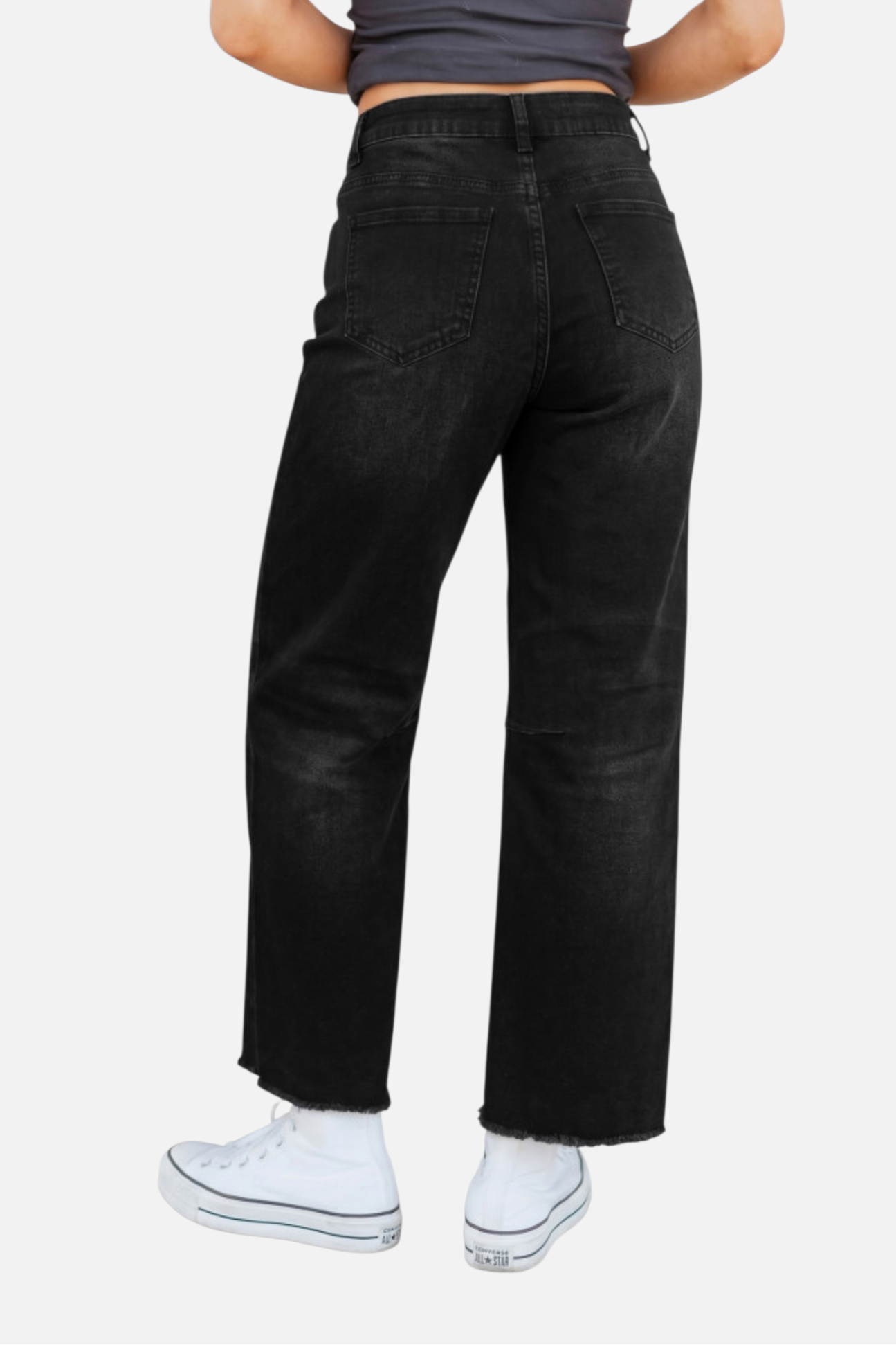 Person wearing black high-waisted jeans on a white background