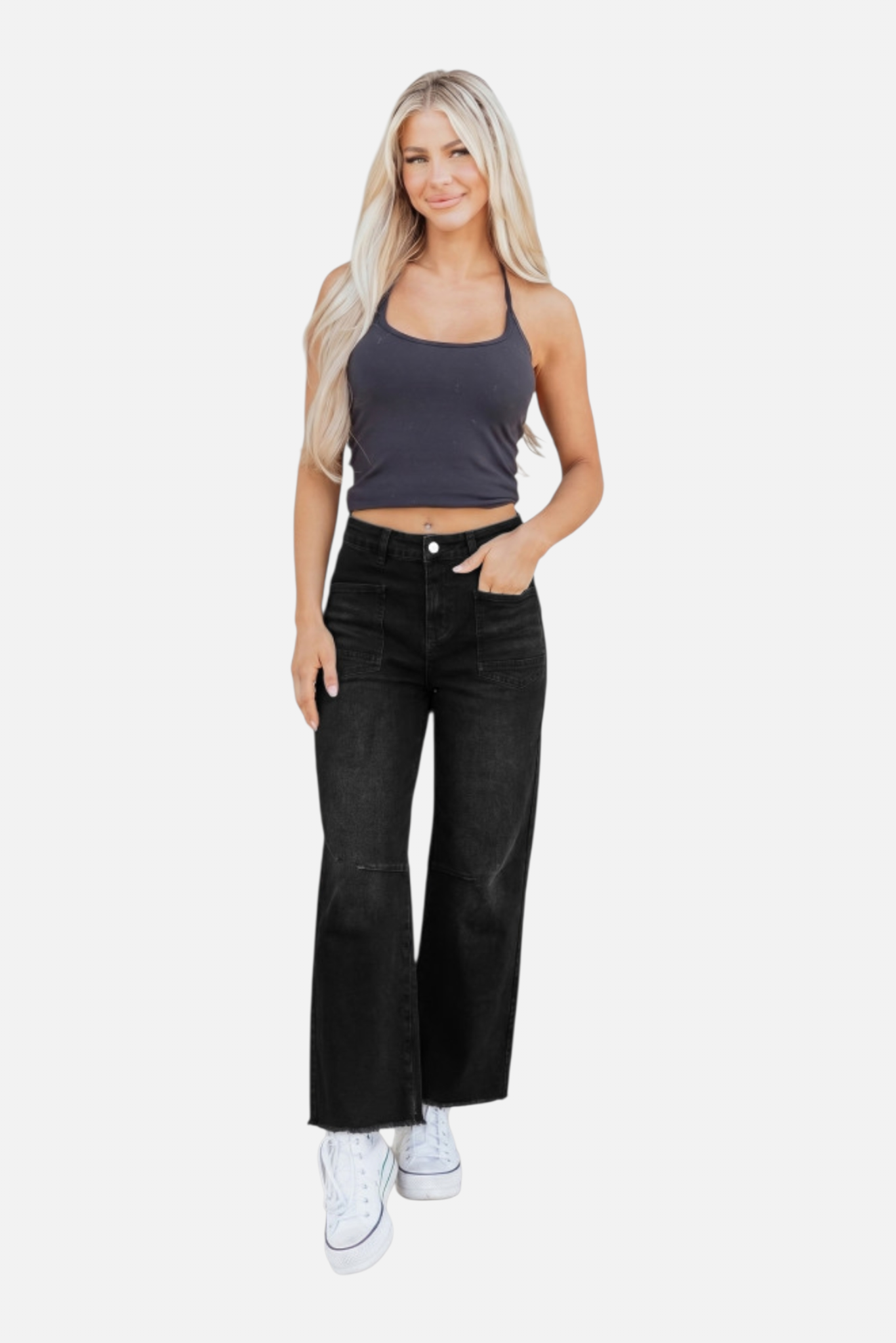 Woman wearing a gray tank top and black jeans on a white background