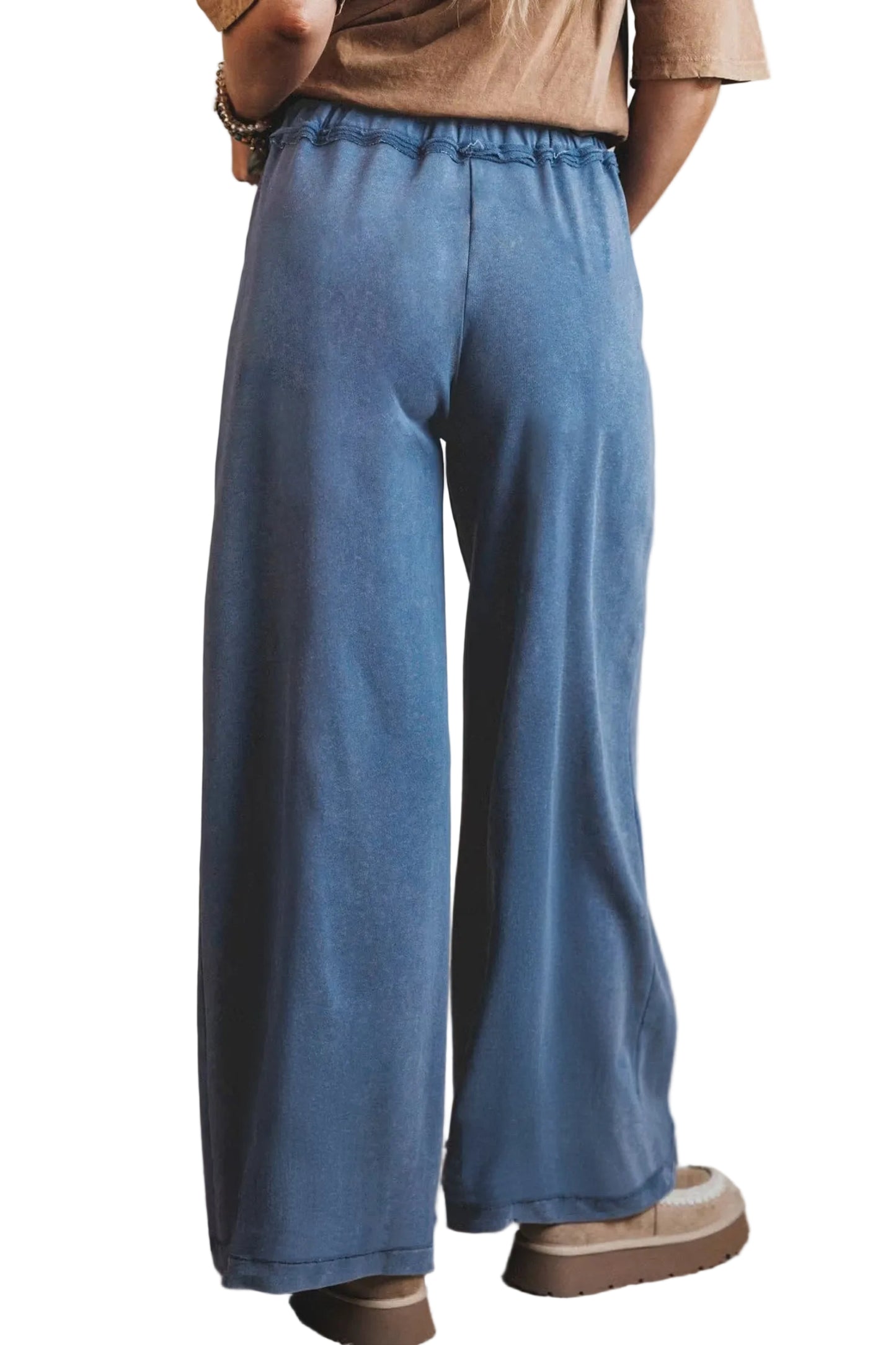 Rear view of the model wearing the washed blue cotton lounge pants, highlighting the relaxed wide-leg fit from behind.