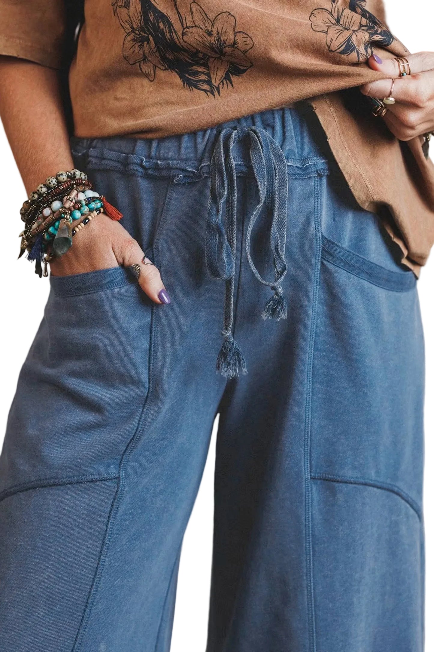 Close-up shot of the elasticated ruffled waistband, adjustable drawcord, and deep front patch pocket on the washed blue cotton pants.