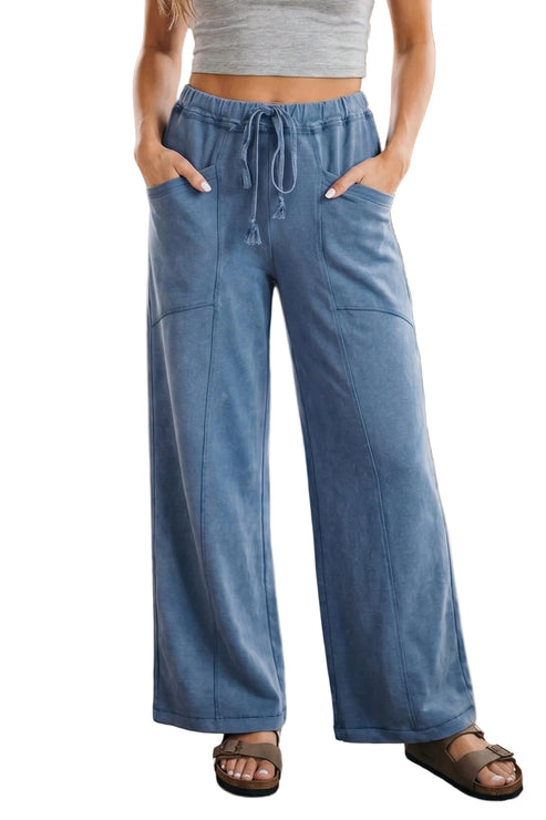 Person wearing blue wide-leg pants and a gray top indoors.