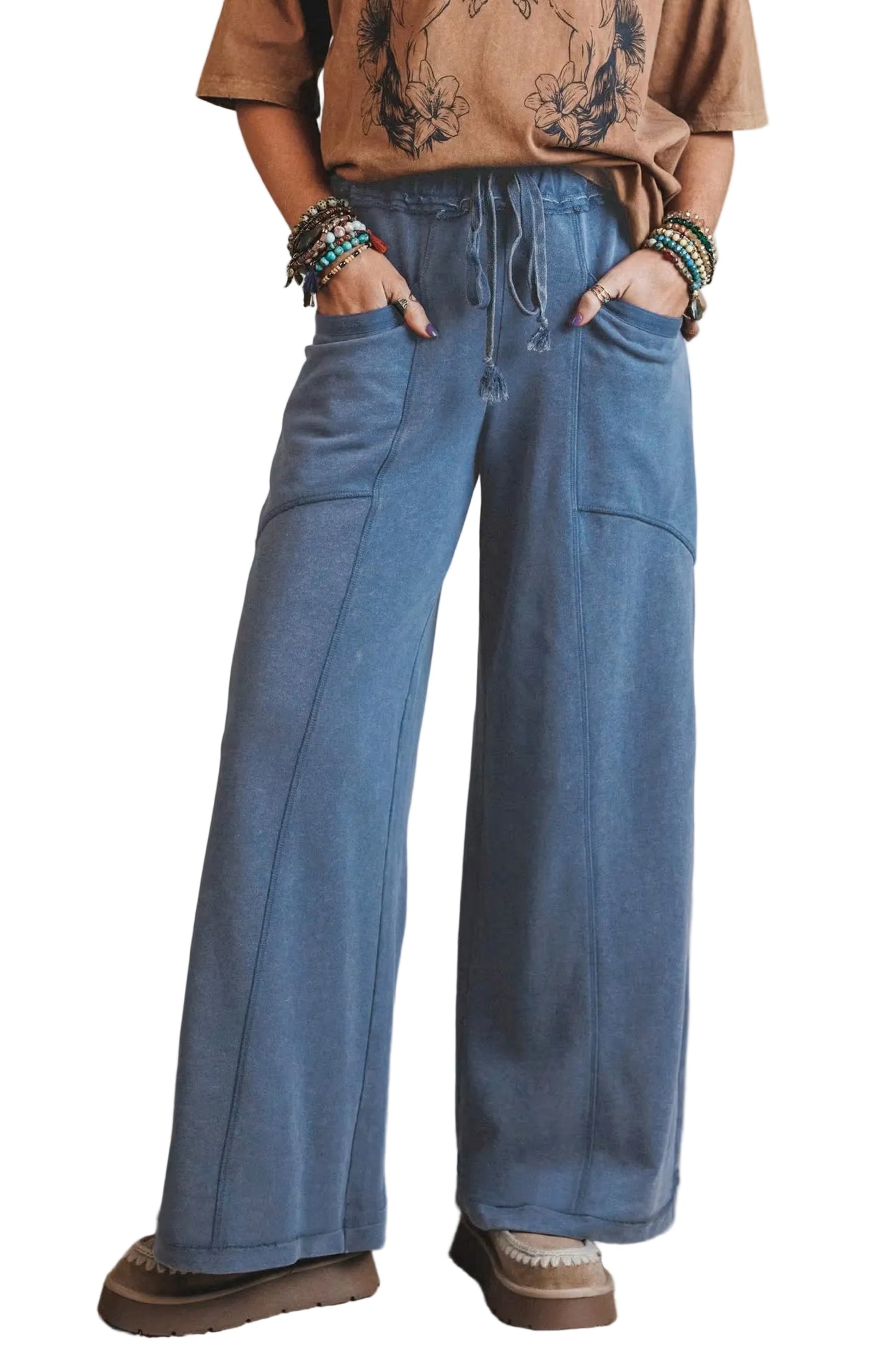 Person wearing blue wide-leg jeans and a brown shirt with a tattoo design, standing against a plain background.