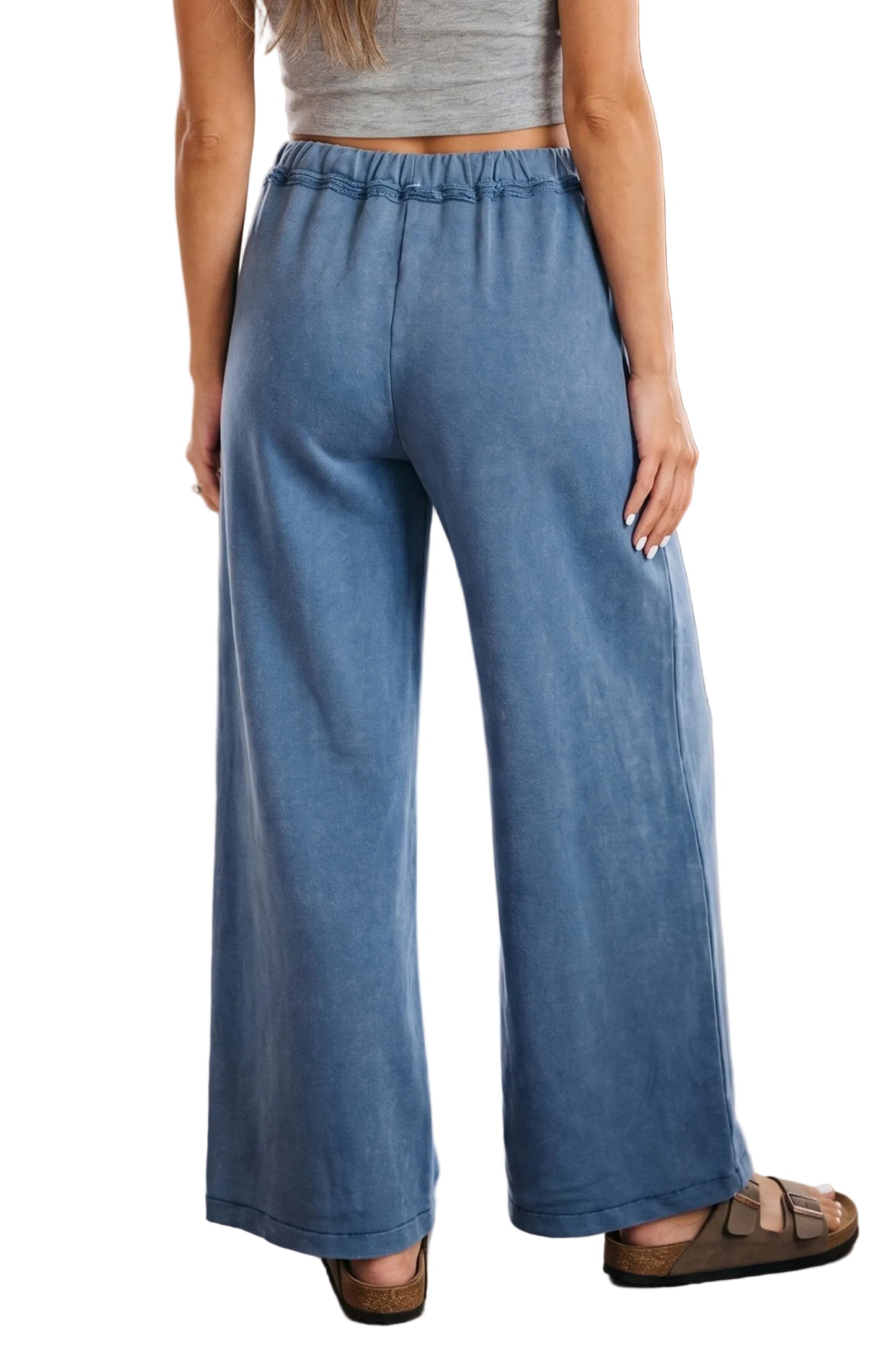 Person wearing blue wide-leg pants and a gray top in a white background.