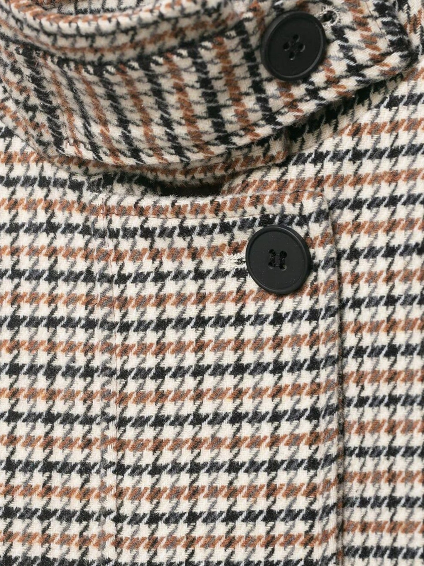 Close-up of a houndstooth fabric with buttons on a patterned background