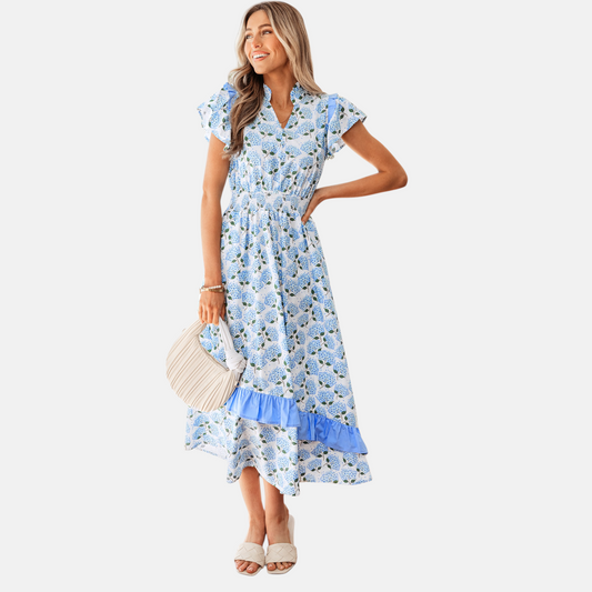 Full-length studio shot of a model in a hydrangea-print midi dress showing the flowy asymmetric hem and flattering smocked silhouette.