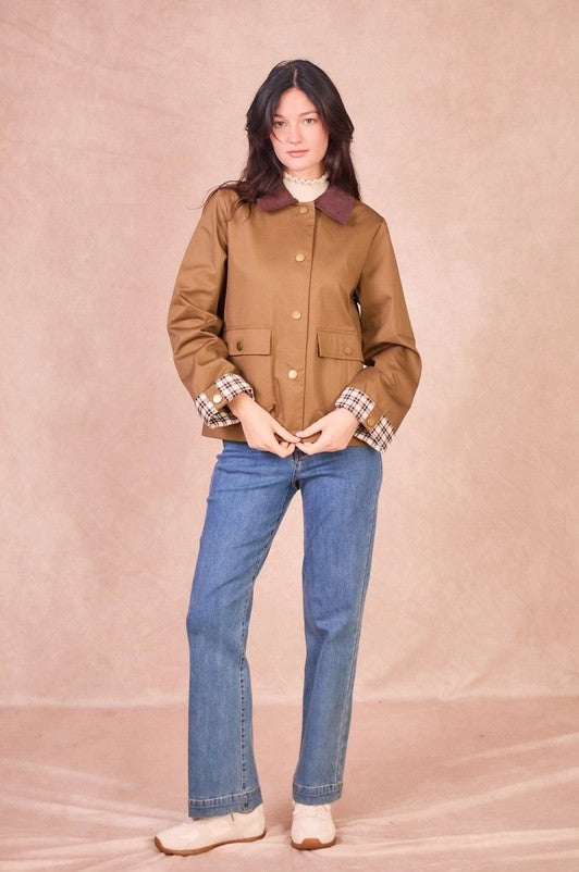Front view of a model wearing a khaki 100% cotton field jacket with a burgundy corduroy collar and checkered turned-up cuffs.