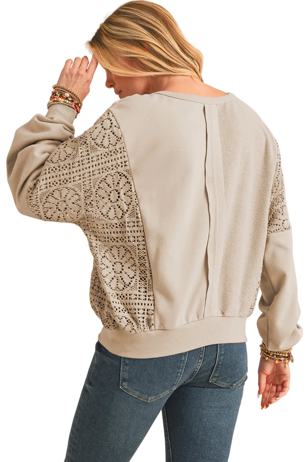 Woman wearing a light gray sweater with lace details on a white background