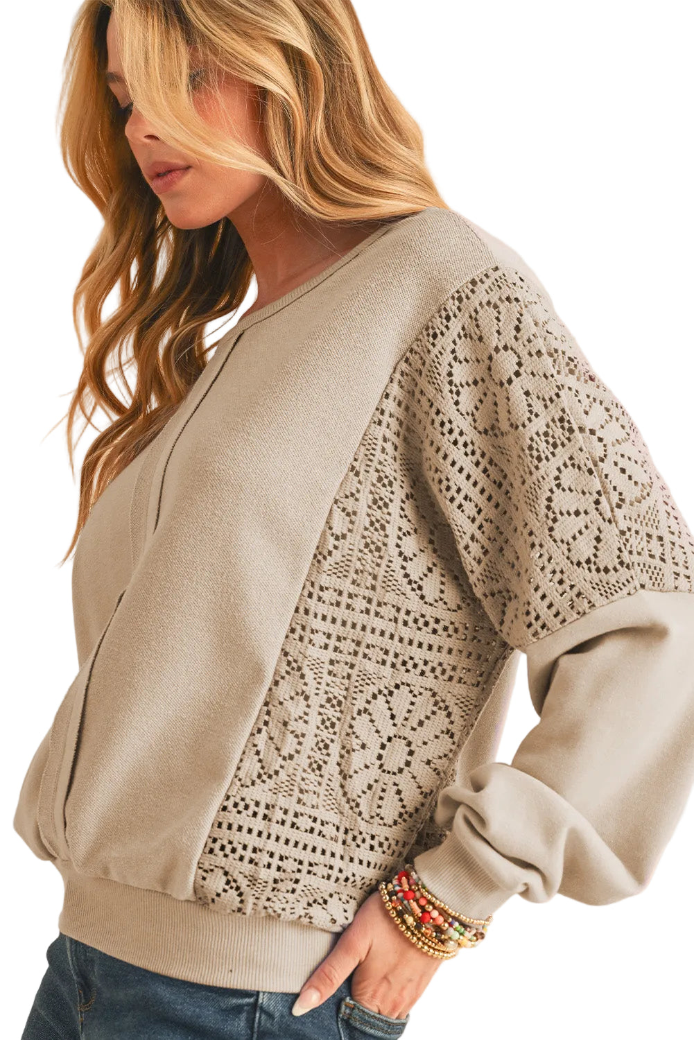 Woman wearing a beige sweater with lace sleeves on a white background