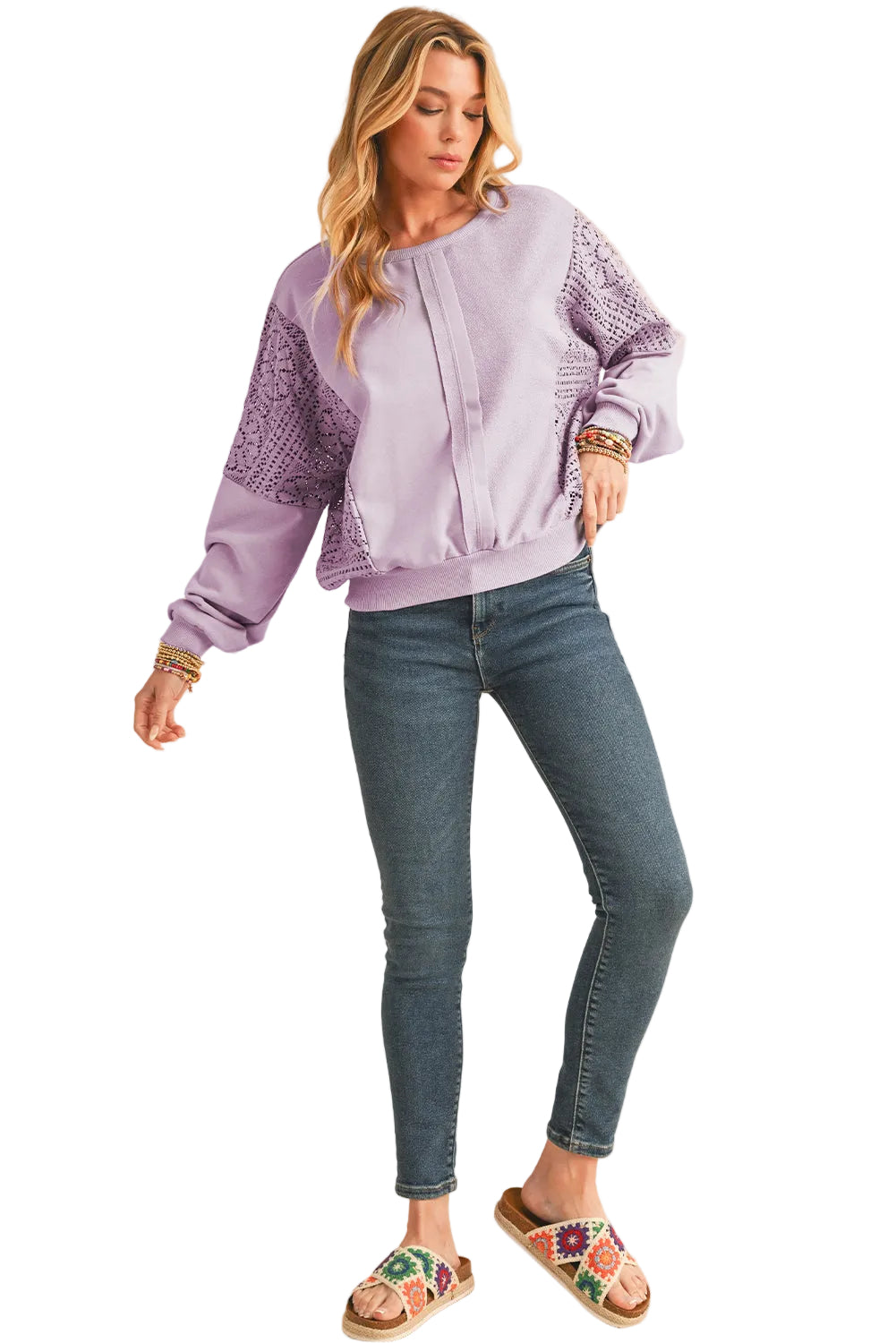 Woman wearing a light purple blouse with lace sleeves and blue jeans on a white background