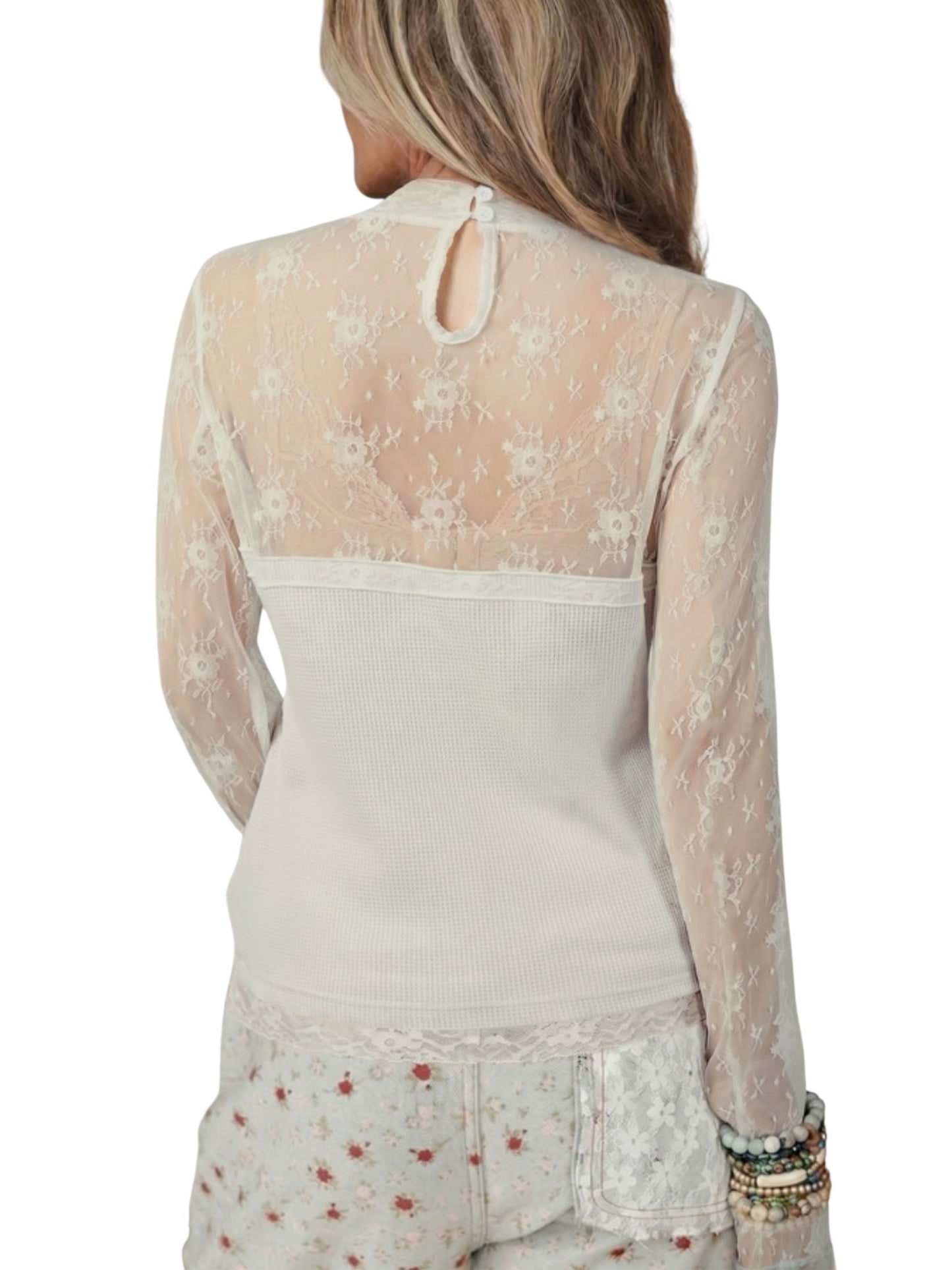 A woman shown from the back wearing a cream-colored long-sleeve top with a sheer floral lace back panel and a small keyhole cutout at the top, paired with matching floral pants against a white background.