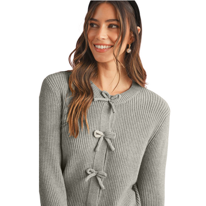Woman wearing a gray textured sweater with bow details on a white background
