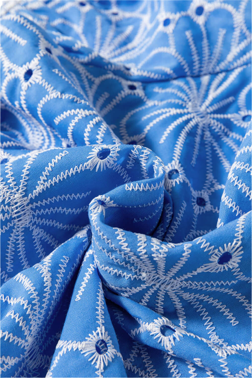 Close-up fabric of floral eyelet details on a lightweight sky blue blouse for women."
