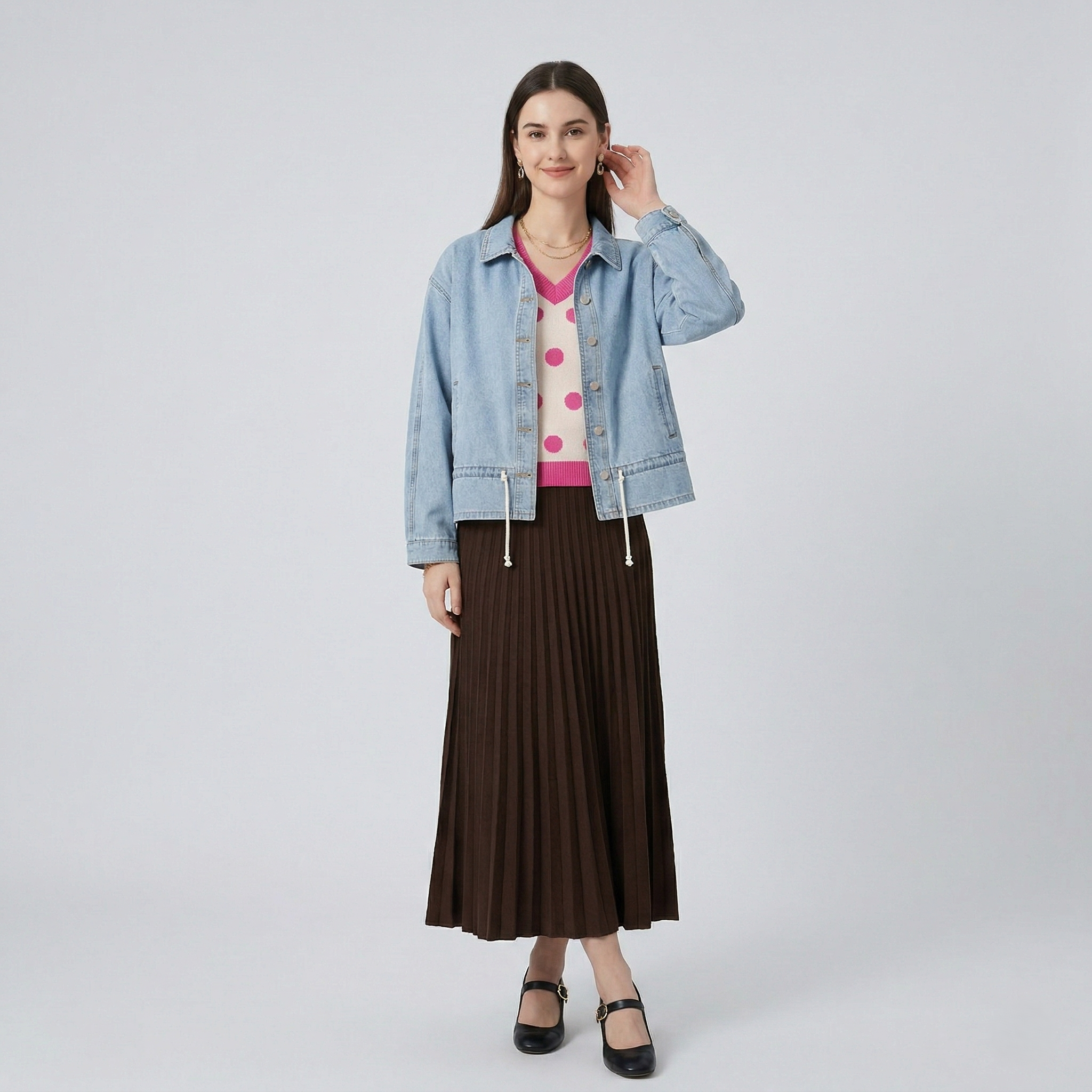 Full-length front view of a model in the adjustable hem denim jacket, showcasing the relaxed fit and versatile styling with a polka-dot sweater and pleated skirt.