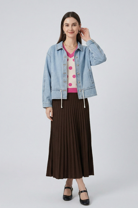 Full-length front view of a model in the adjustable hem denim jacket, showcasing the relaxed fit and versatile styling with a polka-dot sweater and pleated skirt.