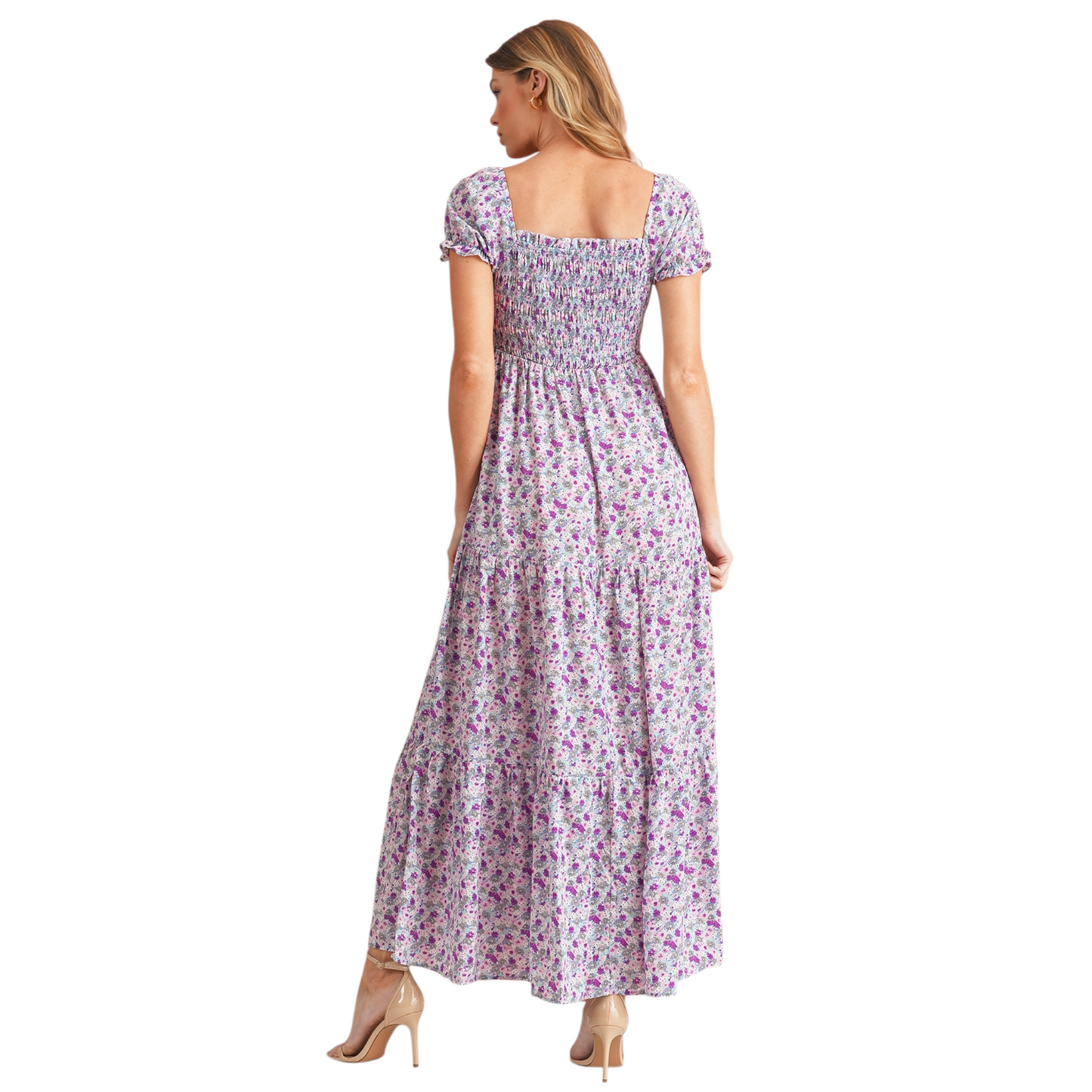 Model wearing a lilac and purple floral smocked maxi dress with short puff sleeves and a tiered skirt. The dress features a square neckline and an elasticated smocked bodice for a flattering fit. Back view.