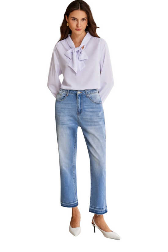 Woman wearing a white blouse with a bow and blue jeans on a white background