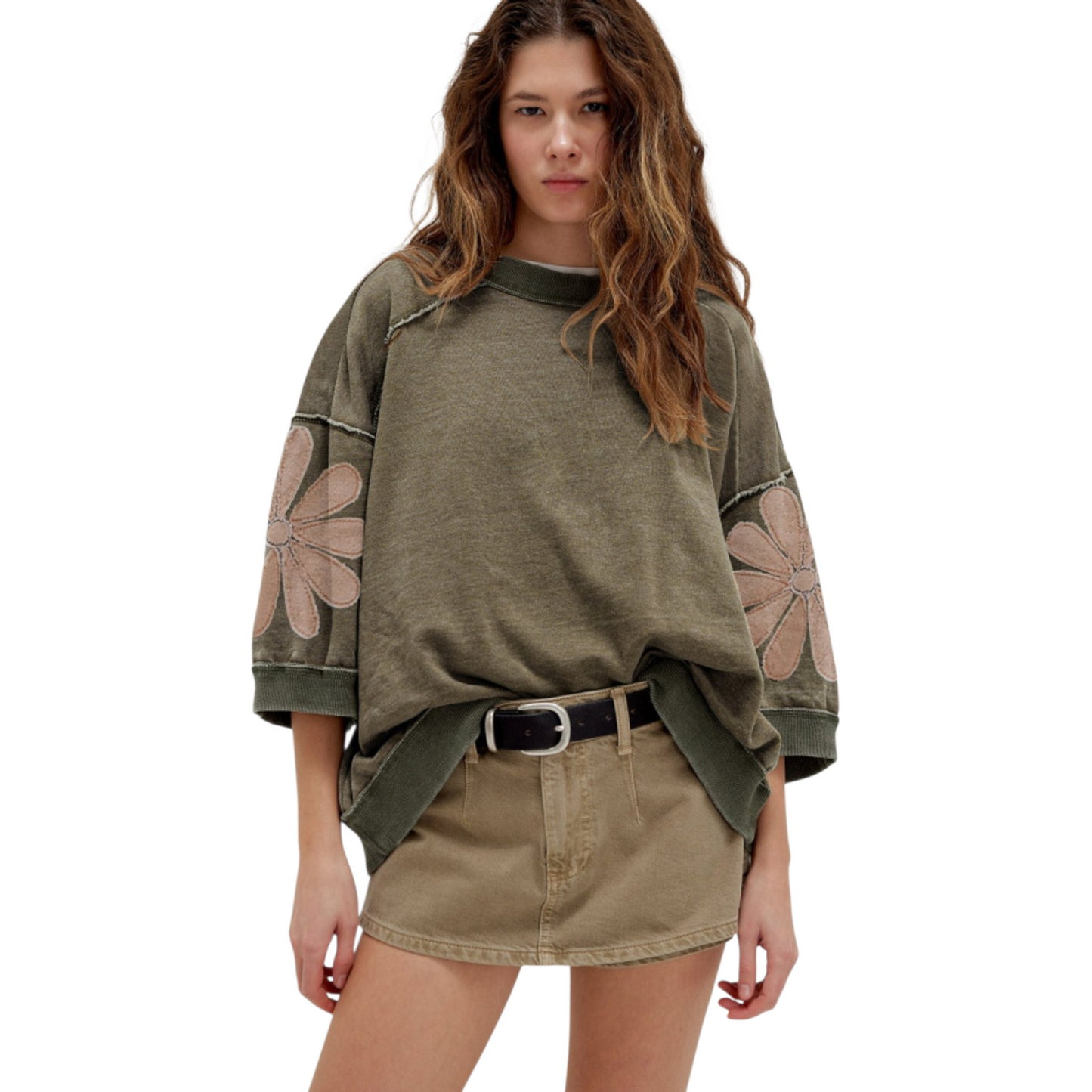 Front view of a model wearing a loose-fit floral patchwork sweatshirt styled with a khaki mini skirt and black belt for a casual, bohemian look.