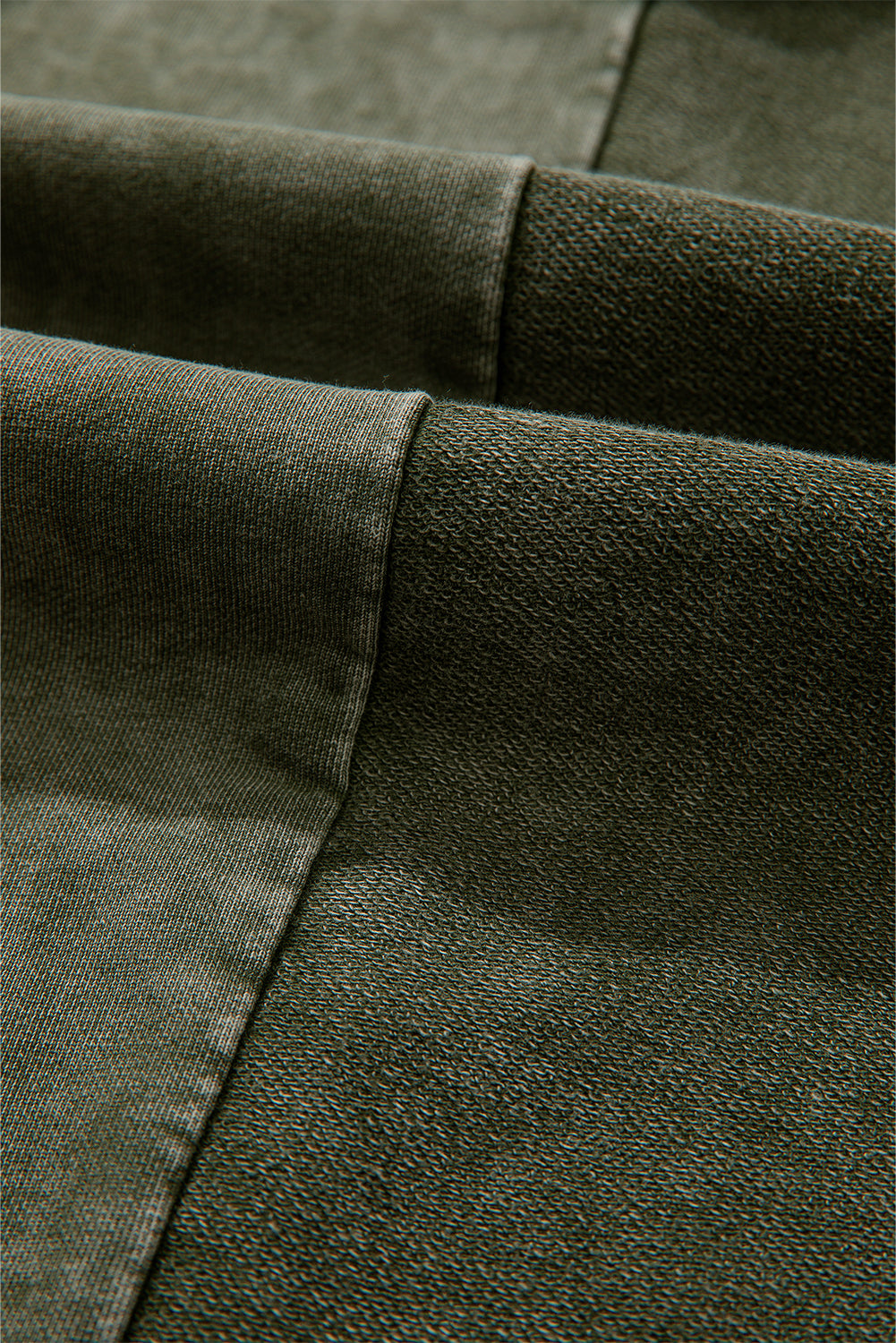 Close-up of green fabric with a focus on texture and stitching detail.