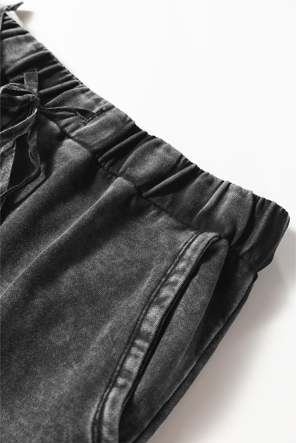 Dark grey denim shorts with a bow detail on a white background