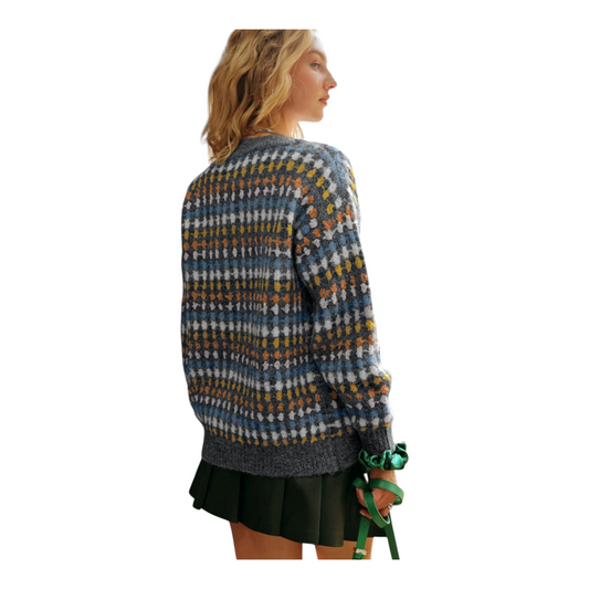 Woman wearing a patterned sweater and skirt holding a green bag on a white background