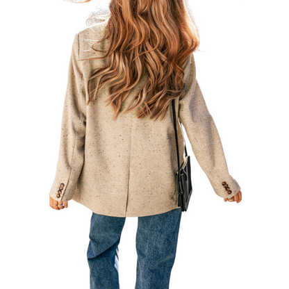 Rear view of a woman wearing a textured oatmeal blazer showing the relaxed tailored fit and long sleeves.
