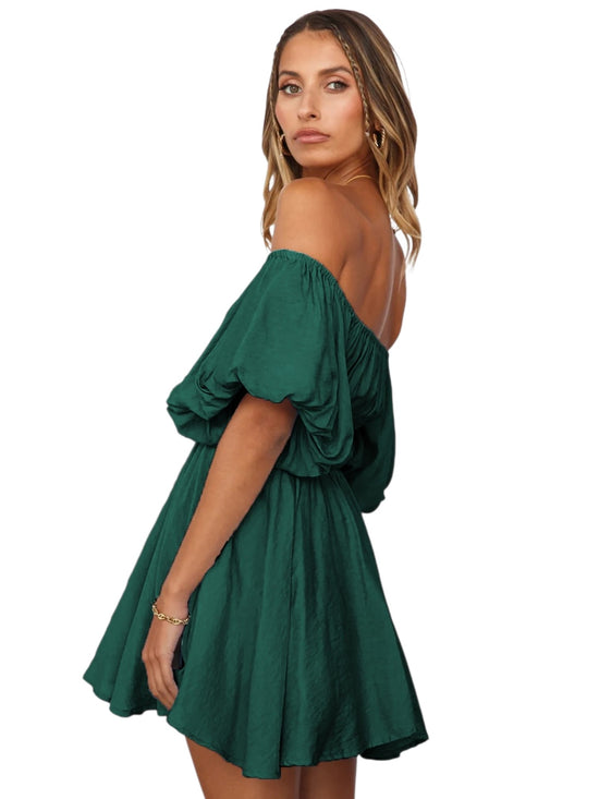 A woman modeling an off-the-shoulder mini dress in emerald green, shown from a three-quarter back angle against a plain white background.